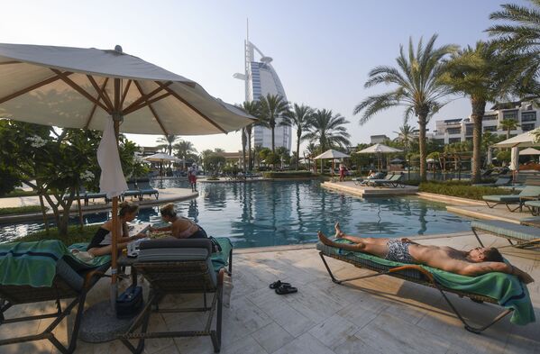 Туристы загорают у бассейна отеля Al Naseem в Дубае в Объединенных Арабских Эмиратах - Sputnik Латвия