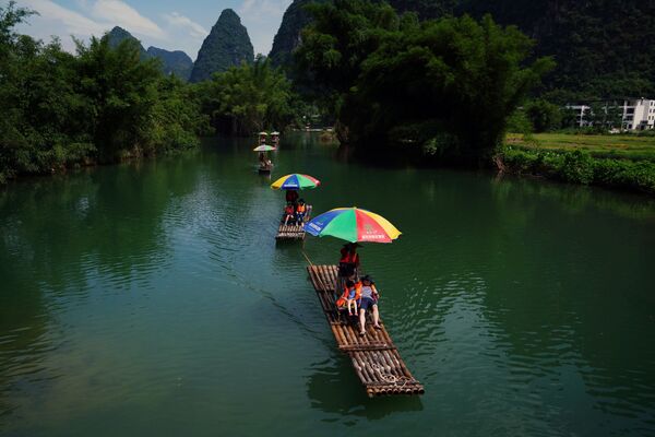 Туристы катаются на плотах по реке Юлонг в округе Яншо, Гуанси-Чжуанский автономный район, Китай - Sputnik Латвия