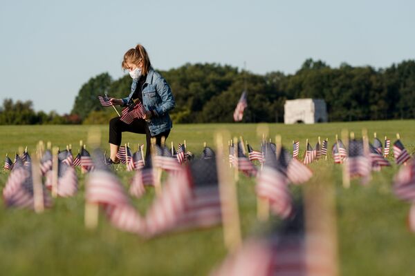 В США число погибших от коронавируса превысило 200 тысяч человек. На фото - молодая девушка в маске размещает флаги Соединенных Штатов в память о погибших от COVID-19 на Национальной аллее в Вашингтоне - Sputnik Латвия