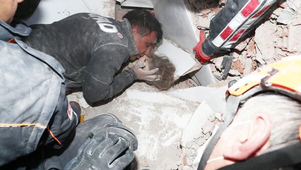 Спасатели вытаскивают ребенка из-под завала после землетрясения в Измире, Турция - Sputnik Латвия