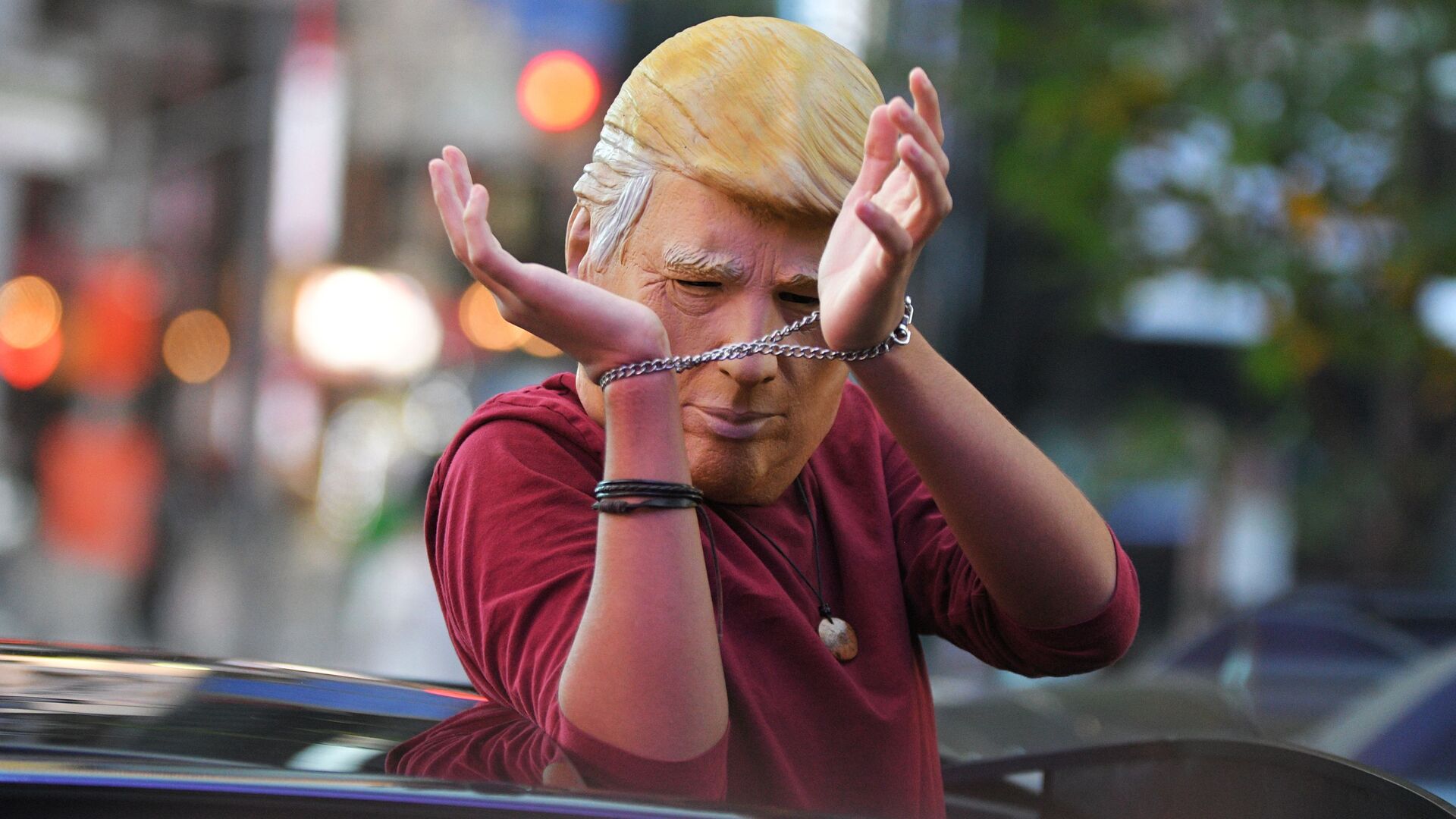 Человек в маске Дональда Трампа едет на машине по улице Нью-Йорка после новостей о победе на выборах президента США кандидата от Демократической партии Джозефа Байдена - Sputnik Латвия, 1920, 15.12.2021