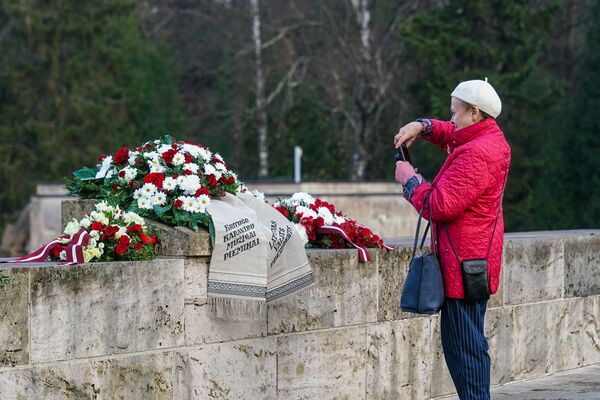 Рижанка фотографирует венки на Братском кладбище в Риге - Sputnik Латвия