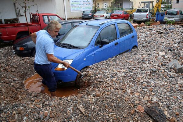 Мужчина выкапывает свою машину после проливных дождей в Малье на острове Крит, Греция - Sputnik Латвия