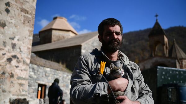 Мужчина держит на руках кота возле храма в монастыре Дадиванк в Нагорном Карабахе - Sputnik Латвия