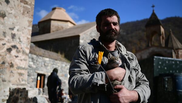 Vīrietis ar kaķi rokās pie baznīcas Dadivankas klosterī Kalnu Karabahā - Sputnik Latvija