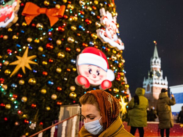 Sieviete aizsargmaskā netālu no Jaungada egles Sarkanajā laukumā Maskavā Sieviete aizsargmaskā netālu no Jaungada egles Sarkanajā laukumā Maskavā - Sputnik Latvija