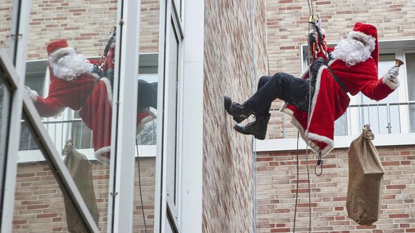 Спасатель в костюме Санты-Клауса спускается с крыши детской больницы в Германии  - Sputnik Latvija
