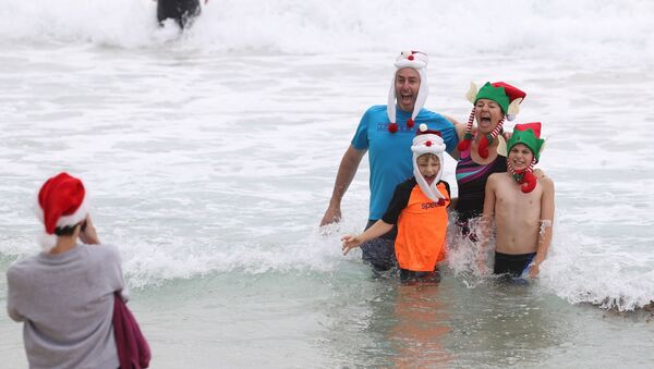 Люди в рождественской одежде позируют для фотографий в Рождество на пляже Бонди в Сиднее, Австралия - Sputnik Latvija