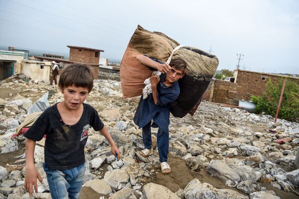 Дети спасают вещи из развалин дома после внезапного наводнения в Чарикаре, провинция Парван, Афганистан - Sputnik Латвия
