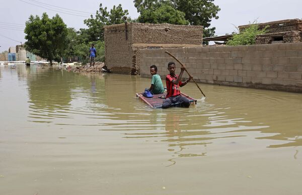 Подростки плывут на плоту по затопленной в результате наводнения улице в городе Салмания, Судан - Sputnik Латвия