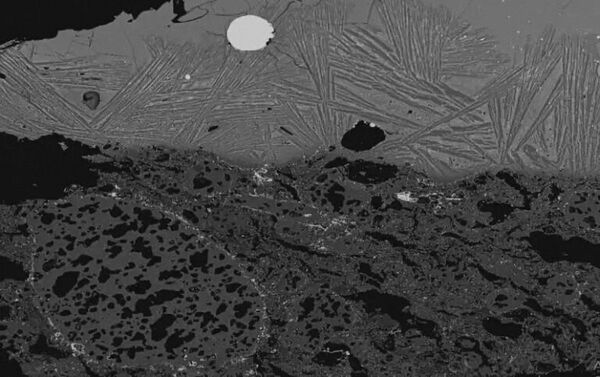 Изображение шлака внутри тигля, полученное с помощью сканирующего электронного микроскопа, с серебристым стальным пятном, видимым в центре вверху - Sputnik Латвия