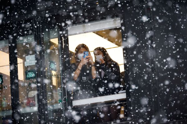 Девушки фотографируют снегопад в Сеуле  - Sputnik Латвия
