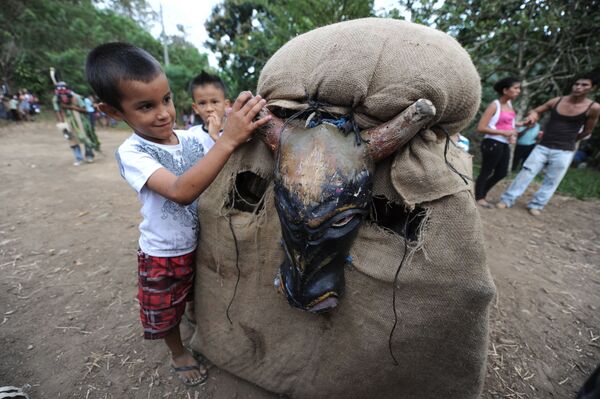 Мальчик играет с участником фестиваля Feast of the Devils в костюме быка в Коста-Рике  - Sputnik Latvija