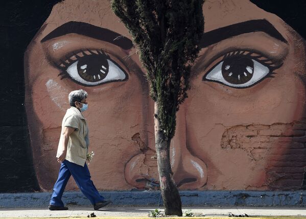 Женщина  проходит мимо граффити на одной из стен кладбища San Nicolas Tolentino в муниципалитете Истапалапа в Мехико - Sputnik Латвия