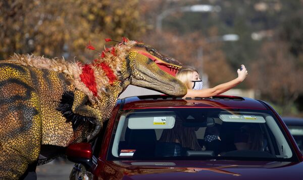 Meitene forografējas kopā ar cilvēku dinozaura tērpā Pasadinā, Kalifornijā, 15. Janvāris - Sputnik Latvija