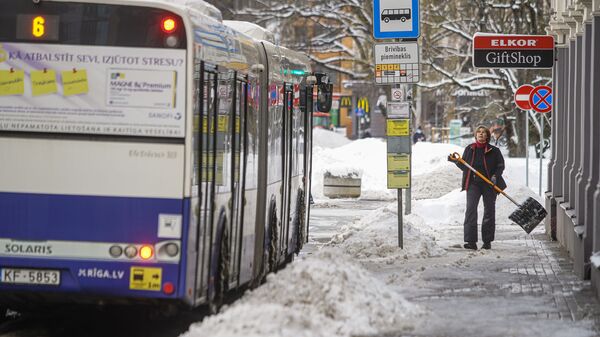 Женщина убирает снег на остановке общественного транспорта - Sputnik Latvija