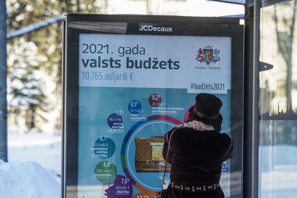 Информационный плакат на остановке общественного транспорта о расходах латвийского бюджета в 2021 году - Sputnik Latvija