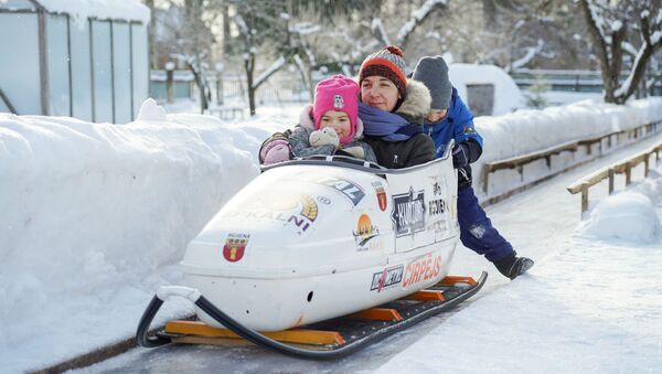 Dana Bērziņa ar bērniem bobsleja trekā, ko viņas vīrs uzbūvējis Rūjienā - Sputnik Latvija