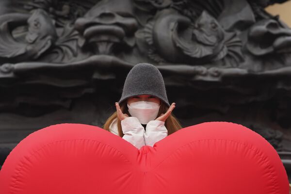 Девушка в маске фотографируется возле воздушного шара в форме сердца в Пекине, Китай - Sputnik Latvija