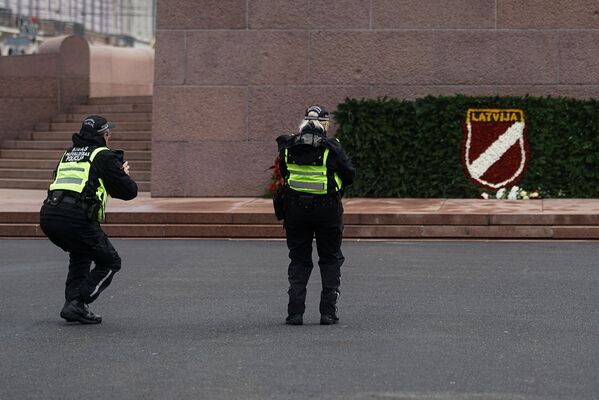 Полицейские возле памятника Свободы в Риге смотрят на венок с эмблемой латышского легиона - Sputnik Латвия