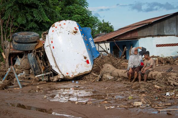 Cilvēki pie bojātas kravas automašīnas pēc negaidītajiem plūdiem, ko radīja tropiskais ciklons Austrumnusas-Tengaras provincē Indonēzijā - Sputnik Latvija