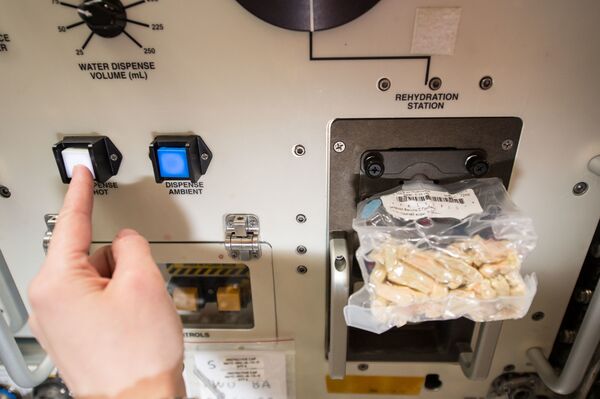 Итальянский астронавт Саманта Кристофоретти во время приготовления обеда на МКС с помощью регидратора космического питания. - Sputnik Латвия