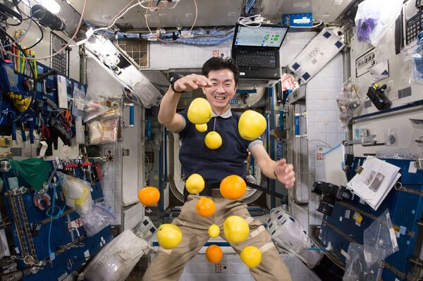 Японский астронавт Кимия Юи собирает летящие фрукты на борту МКС. - Sputnik Латвия