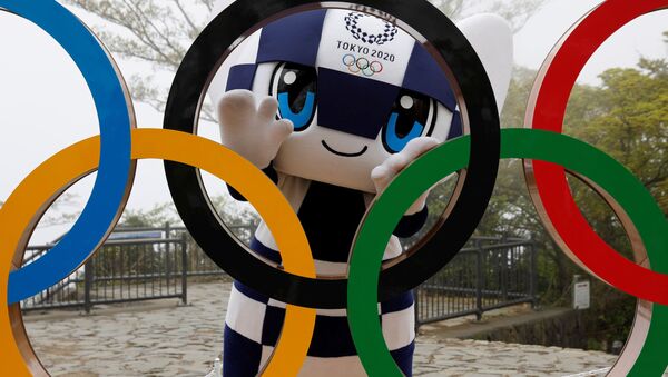 Талисман Летней Олимпиады в Токио Miraitowa позирует сзади олимпийских колец после мероприятия по случаю 100 дней до Олимпийских игр в Токио  - Sputnik Латвия