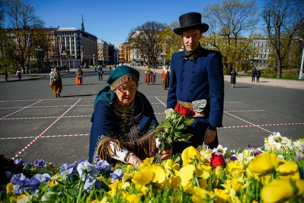 Sieviete un vīrietis tautastērpos noliek ziedus pie Brīvības pieminekļa Latvijas neatkarības atjaunošanas dienā Sieviete un vīrietis tautastērpos noliek ziedus pie Brīvības pieminekļa Latvijas neatkarības atjaunošanas dienā - Sputnik Latvija