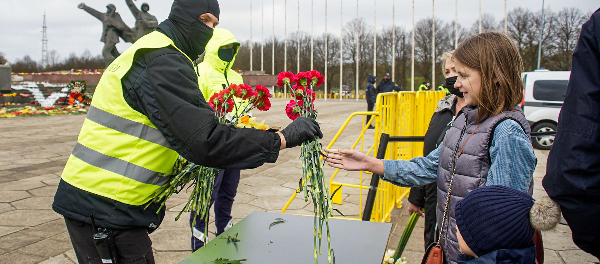 Люди оставляют цветы на столиках, после чего цветы относят к монументу - Sputnik Латвия, 1920, 09.05.2021