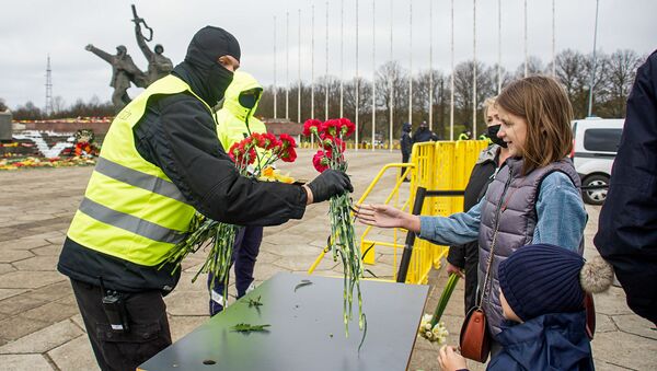 Люди оставляют цветы на столиках, после чего цветы относят к монументу - Sputnik Латвия