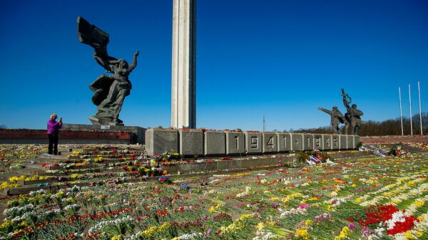 Женщина фотографирует цветы, разложенные у памятника Освободителям Риги - Sputnik Латвия