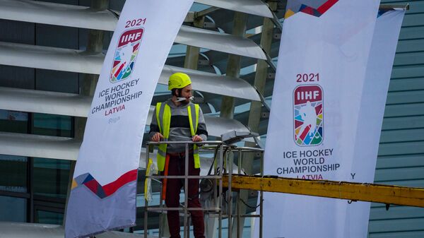 Рабочий вешает флаги с эмблемой Чемпионата мира - 2021 по хоккею в Риге - Sputnik Латвия
