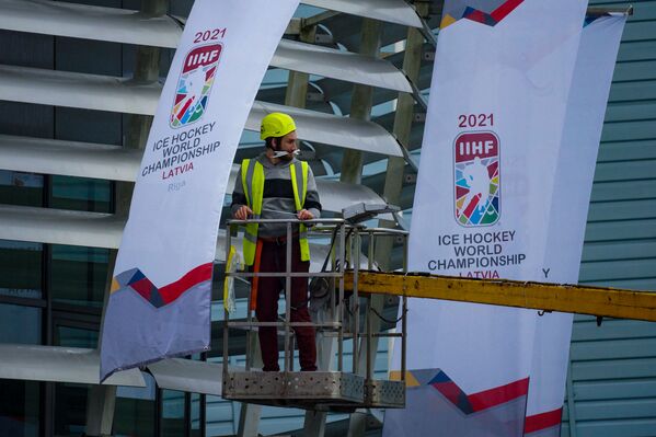 Рабочий вешает флаги с эмблемой чемпионата мира - 2021 по хоккею в Риге. - Sputnik Латвия