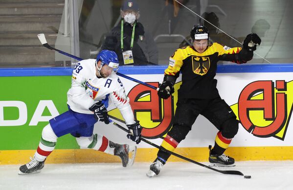 Итальянский хоккеист Маркус Гандер борется за шайбу с Марселем Брандтом из Германии в матче группового этапа чемпионата мира по хоккею - 2021 между сборными Германии и Италии - Sputnik Латвия