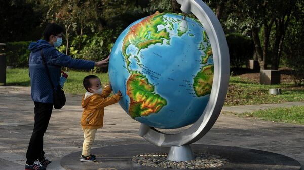 Женщина с ребенком у глобуса в парке в Ухани, Китай - Sputnik Латвия