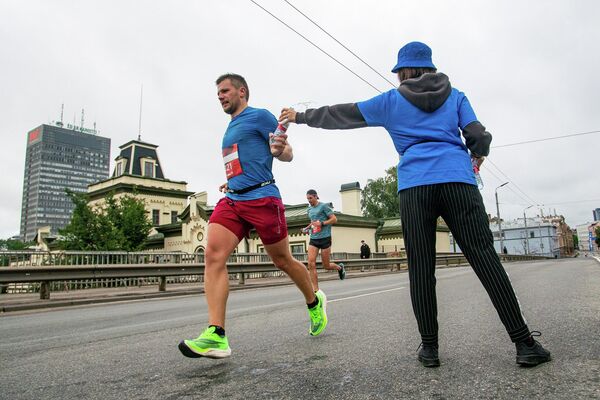 Спортсмен берет бутылку воды на дистанции марафона Спортсмен берет бутылку воды на дистанции марафона - Sputnik Латвия