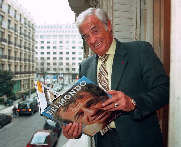 Belmondo kinokarjeru uzskata par vienu no komerciāli sekmīgākajām Francijā. Foto: Belmondo ar sev pašam veltītu grāmatu, 1996. gads - Sputnik Latvija