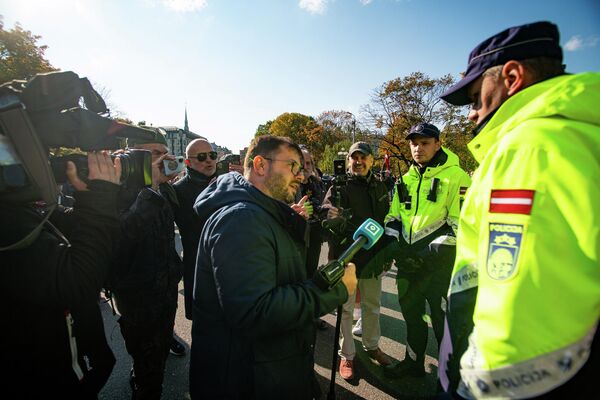 Latvijas televīzijas žurnālists Aleksejs Dunda lūdz policijas darbiniekus aizsargāt viņu un operatoru no uzmācīgiem protestētājiem Latvijas televīzijas žurnālists Aleksejs Dunda lūdz policijas darbiniekus aizsargāt viņu un operatoru no uzmācīgiem protestētājiem - Sputnik Latvija