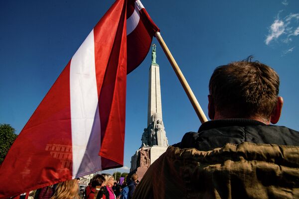 Vīrietis ar Latvijas karogu protesta akcijā pie Brīvības pieminekļa Vīrietis ar Latvijas karogu protesta akcijā pie Brīvības pieminekļa - Sputnik Latvija