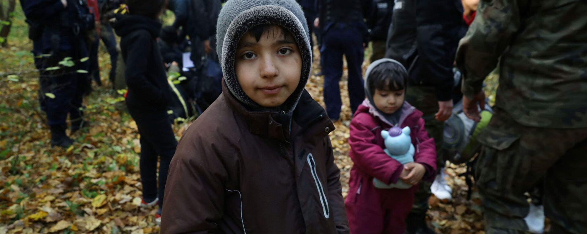 Иракский ребенок в окружении пограничников и полицейских после пересечения белорусско-польской границы в городе Хайнувка, Польша - Sputnik Latvija, 1920, 17.10.2021