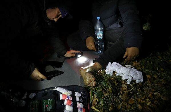 Labdarības organizācijas darbinieks apskata migranta ievainojumu mežā pie pilsētas Sokulka, Polija. Labdarības organizācijas darbinieks apskata migranta ievainojumu mežā pie pilsētas Sokulka, Polija. - Sputnik Latvija
