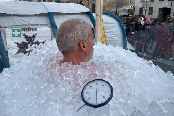 На фото: рекордсмен сидит в ванне со льдом, которую установили в центре Вильнюса. - Sputnik Латвия