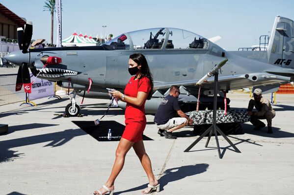Meitene iet garām trieciena lidmašīnai Beechcraft AT-6 Wolverine starptautiskajā aviosalonā "Dubai Airshow 2021" Meitene iet garām trieciena lidmašīnai Beechcraft AT-6 Wolverine starptautiskajā aviosalonā "Dubai Airshow 2021" - Sputnik Latvija