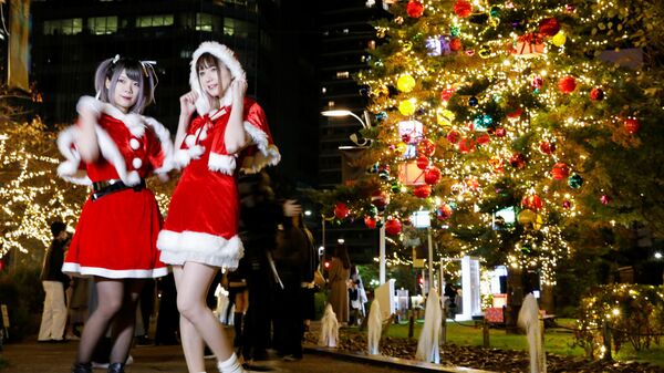 Девушки в костюмах Санта-Клауса фотографируются на фоне рождественских иллюминаций в Токио, Япония - Sputnik Латвия