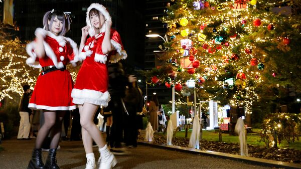 Девушки в костюмах Санта-Клауса фотографируются на фоне рождественских иллюминаций в Токио, Япония - Sputnik Latvija