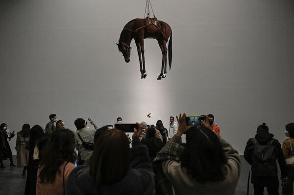 Cilvēki fotografējas pie itāļu mākslinieka Mauricio Katelāna skulptūras &quot;Novecento&quot; izstādē Pekinas Modernās mākslas centrā, 20. novembris - Sputnik Latvija