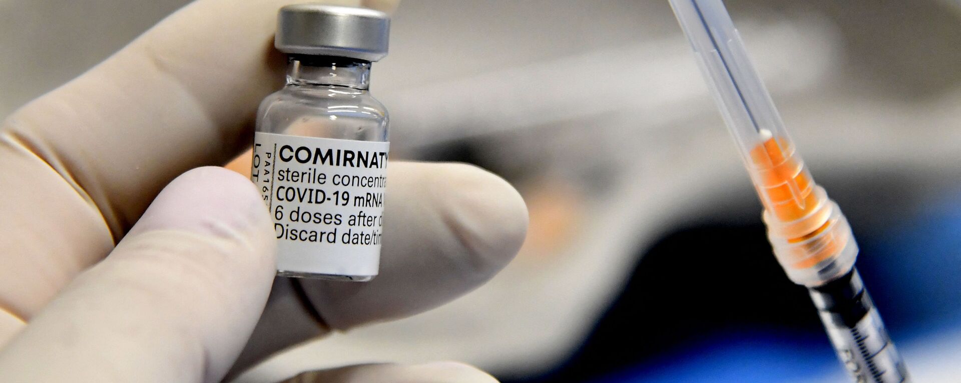 Медицинский работник держит шприц и флакон вакцины Comirnaty от Pfizer-BioNTech против Covid-19, Италия - Sputnik Латвия, 1920, 02.12.2021