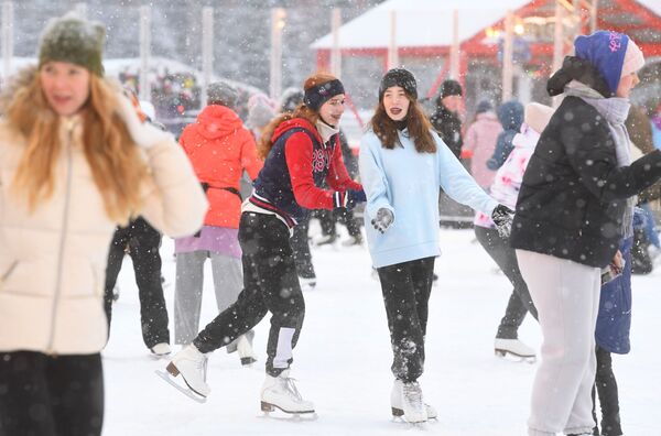 Люди катаются на коньках на площадке ГУМ-катка в Москве во время снегопада - Sputnik Латвия