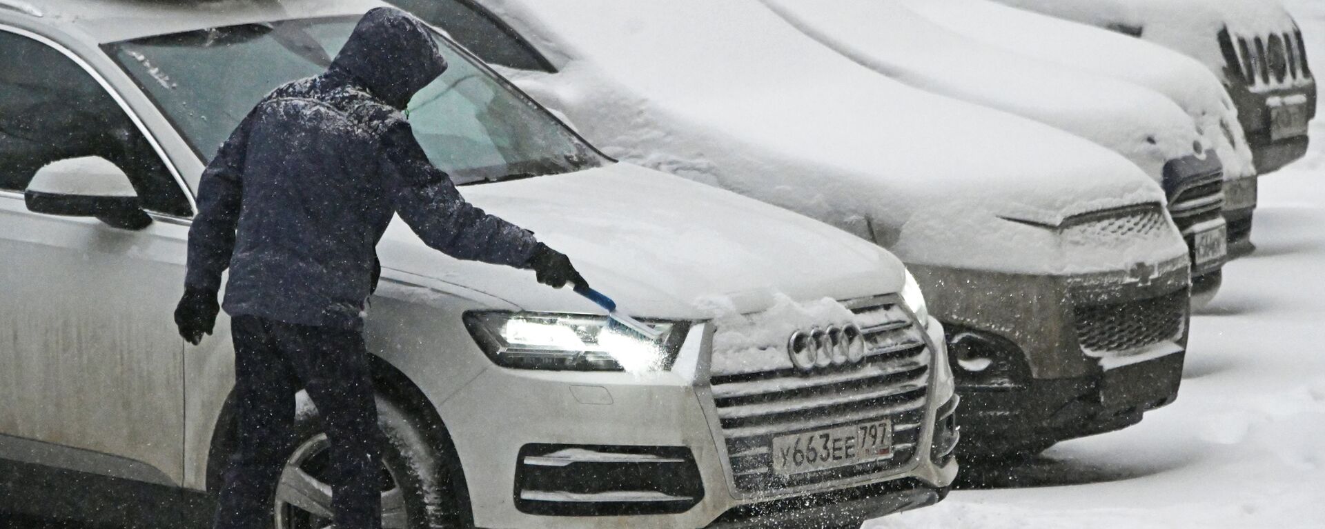 Мужчина чистит от снега свою машина во время снегопада в Москве - Sputnik Латвия, 1920, 09.01.2022